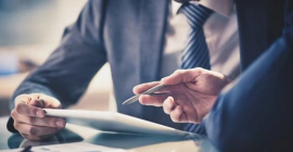 A professional's hands meticulously examining papers and graphs, reflecting a focused approach to business analysis